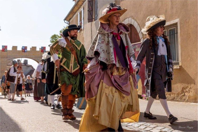 Des personnes en costumes d'époque, nobles, chevaliers, clergé, paysans dans la rue de Lupiac menant à la place